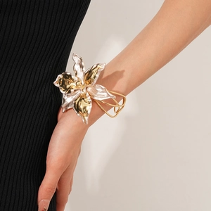 Detailed close-up of a large cutout lily flower bracelet in mixed gold and silver tones