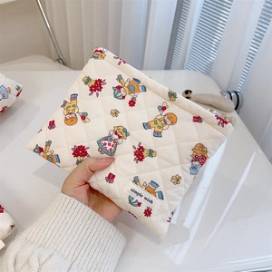 Close-up of a quilted floral cosmetic bag held by hand to show size and cotton texture