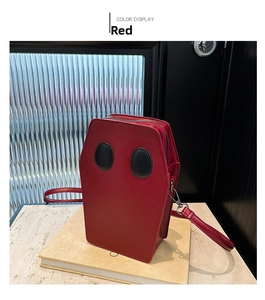 Detailed close-up of a red coffin-shaped leather crossbody bag with black eye patches