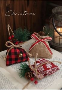 Close-up of linen Christmas gift bags with pine cones and berries on vintage books