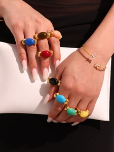 Model wearing various colorful resin rings with gold plating and butterfly bracelet