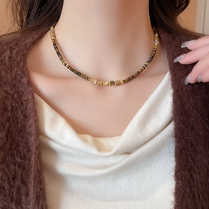 Detail of vintage tiger eye and pearl beaded necklace on model with golden accents