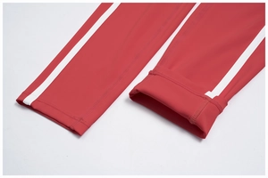 Detail of flatlock stitching and white side stripes on red yoga leggings cuff