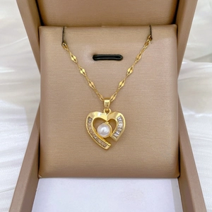 Detail of gold heart pendant necklace with pearl and sparkling crystals in a gift box