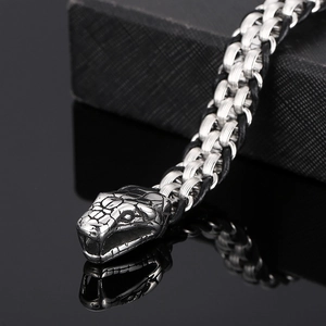 Detail of a men's woven stainless steel bracelet featuring a realistic snake head clasp