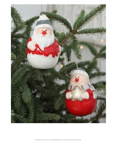 Gros plan d'ornements Père Noël rouge et blanc suspendus à un sapin avec lumières chaudes