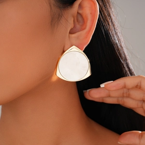 Close-up of a large 14K gold plated triangular earring with white shell inlay on model