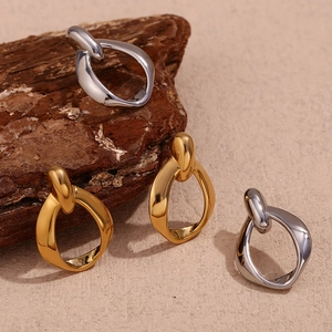 Detail of twisted hoop earrings in gold and silver finish on a textured background