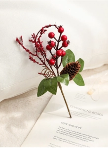 Close-up of Christmas berries and pine cones arranged over a book in a cozy setting