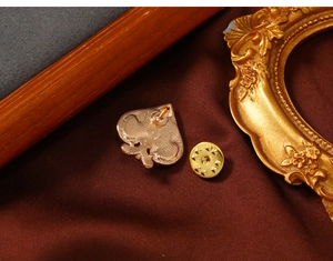 Macro detail of a golden heart poker lapel pin on a premium dark velvet background