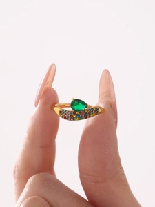 Dettaglio anello dorato con zircone verde a goccia e micropavé di pietre multicolore