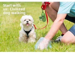 Green capsule poop bag dispenser with LED attached to a red leash on outdoor grass