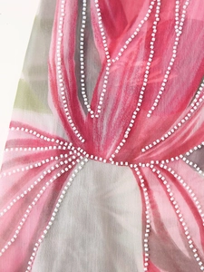 Gros plan sur les perles blanches brodées sur un tissu floral rose et gris doux