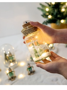 Close-up of a festive glass Christmas snow globe with LED pine tree and fake snow