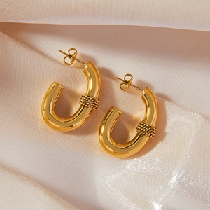 Gold-plated stainless steel U-shaped hoop earrings with a textured twist design on silk