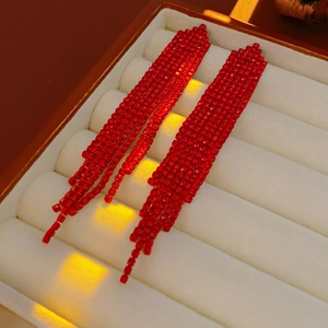 Detailed close-up of red rhinestone fringe earrings on a white velvet jewelry tray