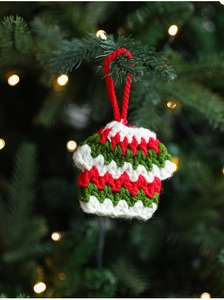 Close-up of handmade crochet Christmas sweater ornament with red and green yarn