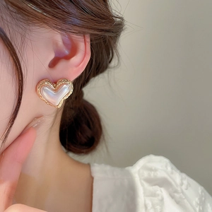 Elegant gold metal heart stud earrings with faux pearl inlay worn by a model