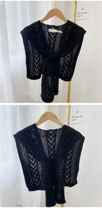 Close-up of black hollow knit shawl with intricate crochet pattern and knot closure