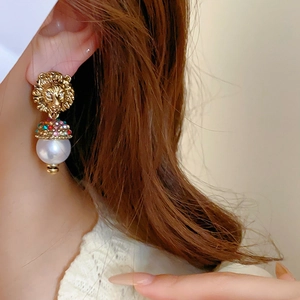 Detail of lion head earring with colorful crystals and white round imitation pearl