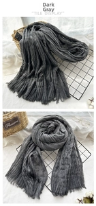 Detailed macro view of charcoal grey oversized scarf with pleated texture and frayed edges