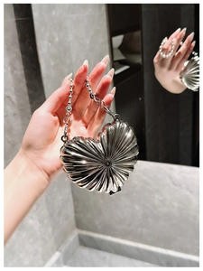 Detailed view of silver heart-shaped mini bag with pleated metallic texture and bead chain