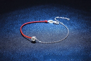 Detail view of red rope and silver chain bracelet featuring a round solitaire moissanite