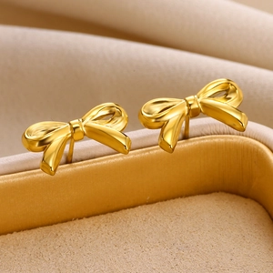 Macro shot of gold bow stud earrings with polished mirror finish on velvet jewelry box