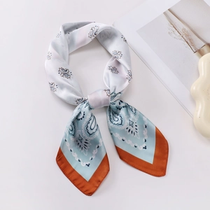Detail of light blue paisley silk scarf with orange borders and smooth satin texture