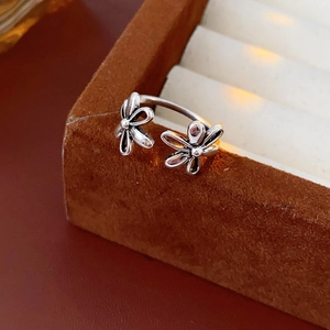 Macro shot of silver hollow double flower open ring on brown velvet jewelry box