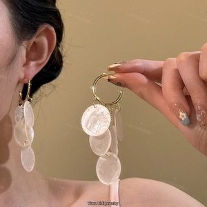 Macro detail of bohemian gold circular earrings with translucent white tassel pendants