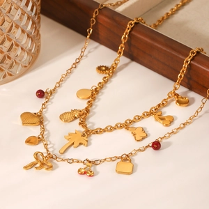 Detail of gold double-layer necklace with tropical charms like coconut tree and cherry