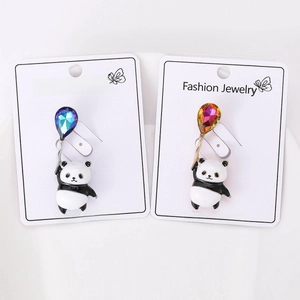 Detail view of two cute panda brooches with colorful rhinestone balloons on a white plate
