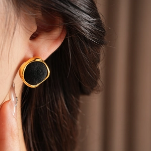 Détail rapproché de boucles d'oreilles géométriques en or et velours noir sur un mannequin