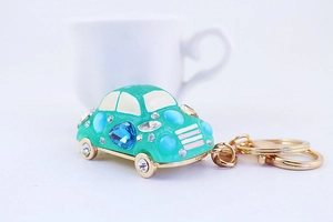 Close-up of green crystal car keychain with colorful gemstones and gold keyring hardware