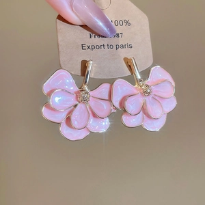 Macro detail of elegant pink enamel flower earrings with gold finish and double petals