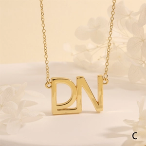 Detailed view of golden necklace featuring DN initial letter pendant with zircon accents