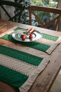Detail of woven cotton Christmas placemat with green stripes and decorative tassels