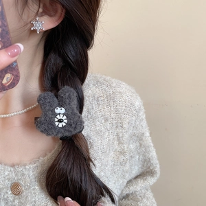 Close-up of a plush grey rabbit head hair clip worn on a woman's hairstyle