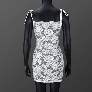 Détail du tissu en dentelle florale blanche et des bretelles à nouer sur la robe courte