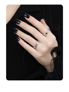 Detail of silver rings with black diamond-shaped resin and heart pattern on model hand