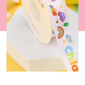 Close-up of white decorative ribbon with colorful car and rainbow cartoon prints for gift DIY