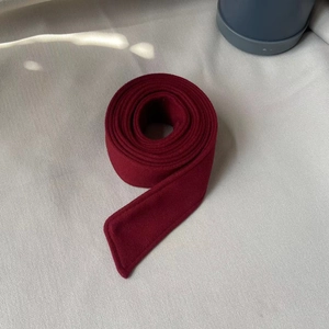 Detail of deep red wool belt for winter coat showing high-quality double stitching