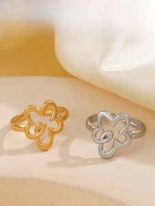 Detail of gold and silver cutout flower rings on sand background with silk fabric