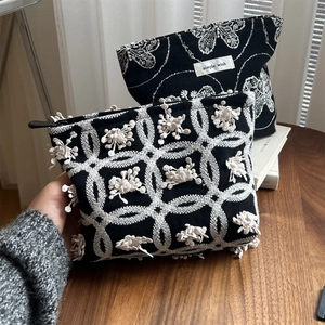 Close-up of black canvas makeup bag with 3D white lace butterfly floral embroidery