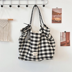 Close-up of black and white checkered tote bag with woven strap and branded label