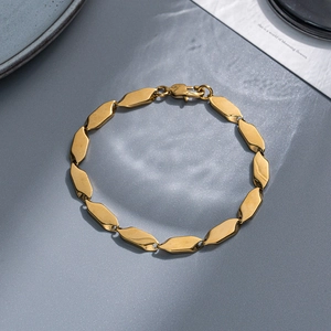 Detailed view of golden geometric diamond links and lobster clasp on a steel bracelet