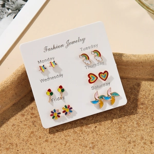 Detail of six pairs of colorful enamel fruit stud earrings on a weekly card display