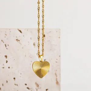 Detail view of 18K gold plated heart pendant with sunburst texture and water wave chain