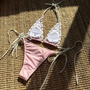 Detailed view of white lace-up bikini top and pink bottoms on a textured sisal carpet